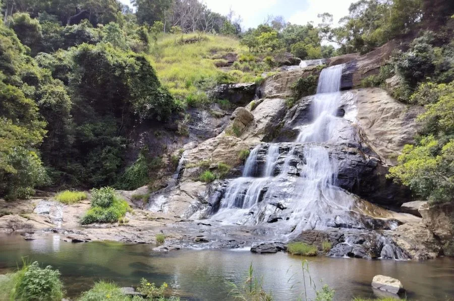 Cascading waterfall amidst lush green hill country landscapes