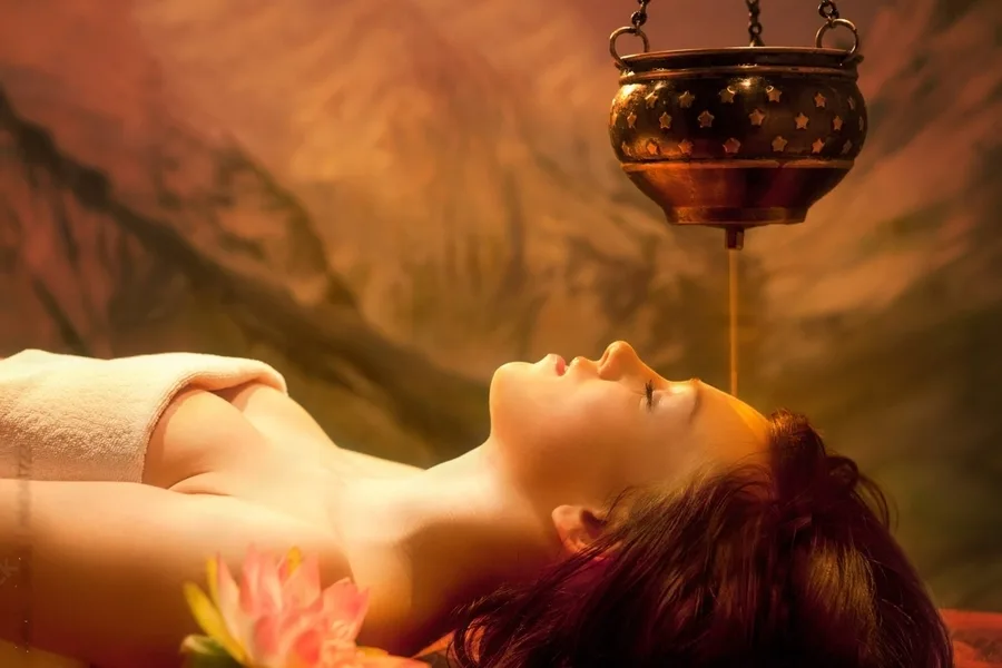 Shirodhara warm medicated oil stream poured over the forehead