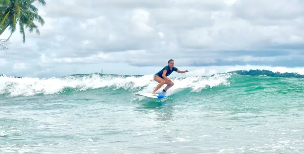 Female surfer catching a clean peeling wave at Weligama Beach