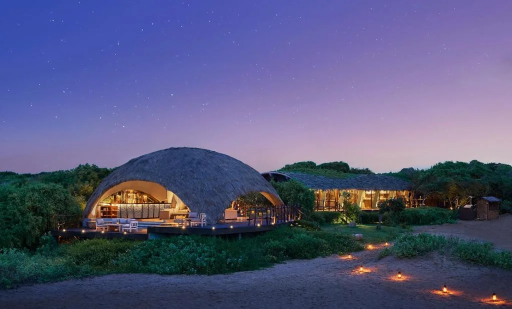 Night view of illuminated private plunge pool cabin at Uga Chena Huts